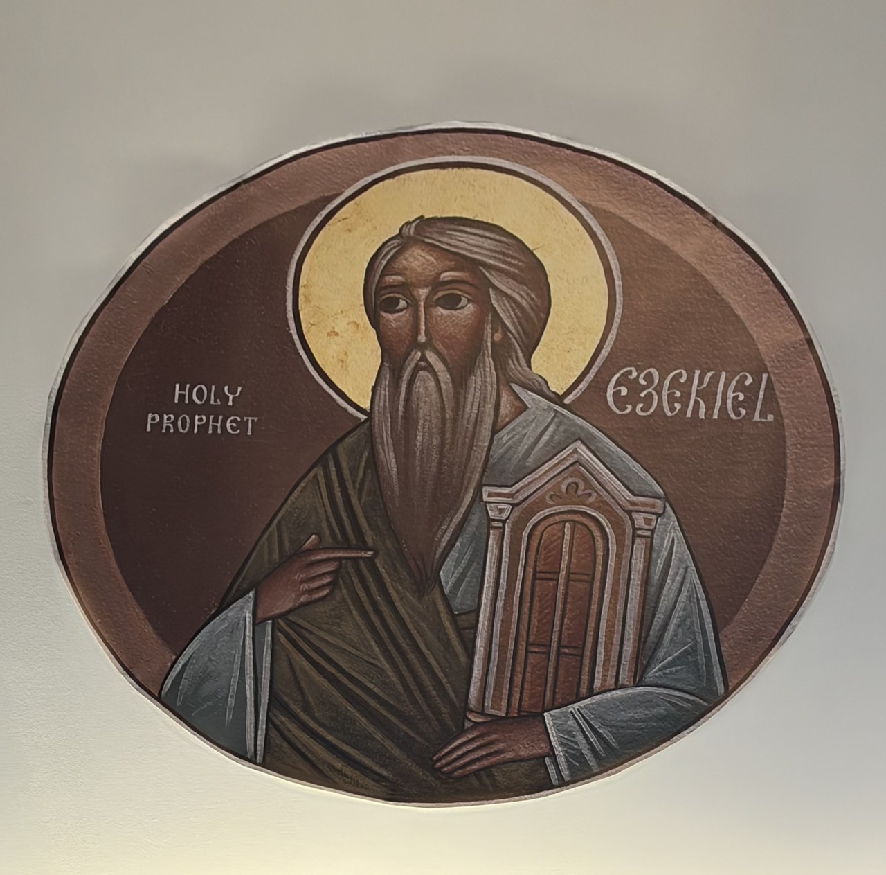 Church icon of the prophet Ezekiel holding a closed gate, with a gold halo and burgundy background.